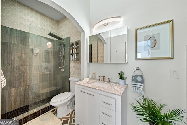 full bathroom featuring tiled shower, vanity, and toilet