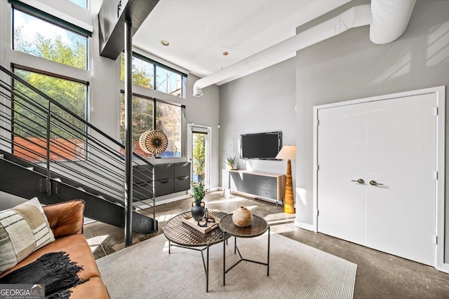 living area with a towering ceiling and concrete flooring