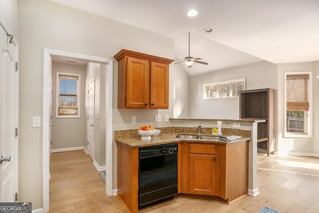 kitchen with black dishwasher, brown cabinets, a peninsula, light stone countertops, and a sink