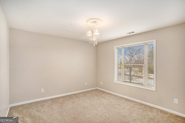 carpeted spare room with an inviting chandelier, baseboards, and visible vents