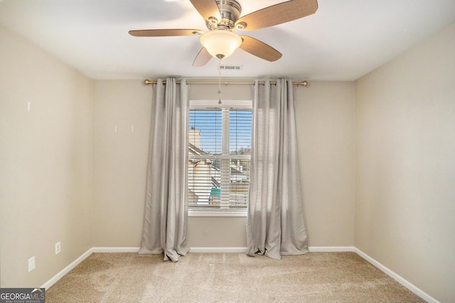 carpeted spare room with a ceiling fan, visible vents, and baseboards