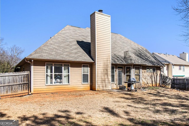 rear view of house with a patio area, fence, a chimney, and roof with shingles