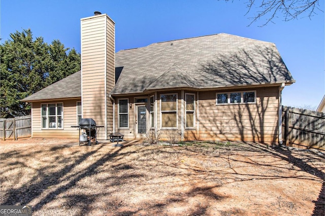 back of property featuring a chimney and fence