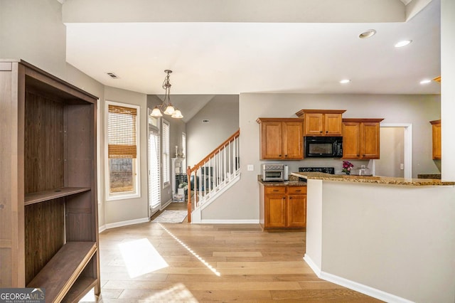 kitchen featuring light wood-style flooring, black microwave, brown cabinetry, and a notable chandelier