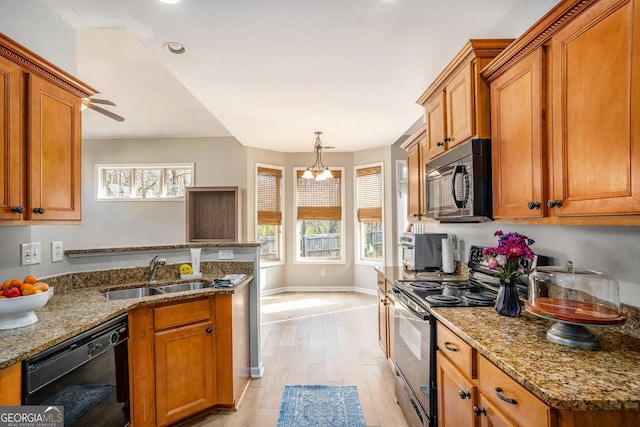 kitchen featuring brown cabinetry, a healthy amount of sunlight, a sink, and black appliances