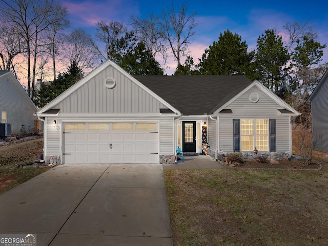 ranch-style home with driveway, a shingled roof, an attached garage, central air condition unit, and board and batten siding