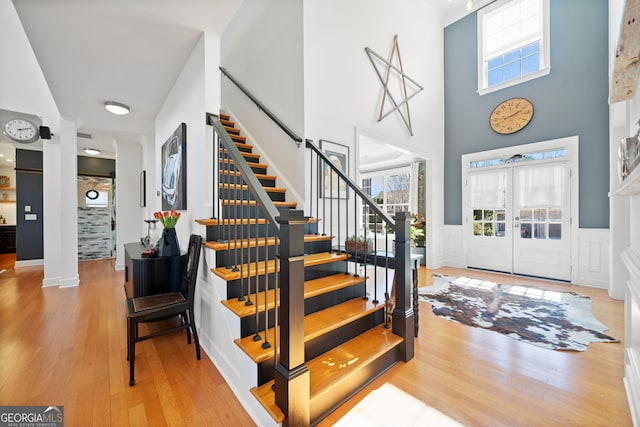 entryway featuring wainscoting, hardwood / wood-style floors, stairway, and plenty of natural light