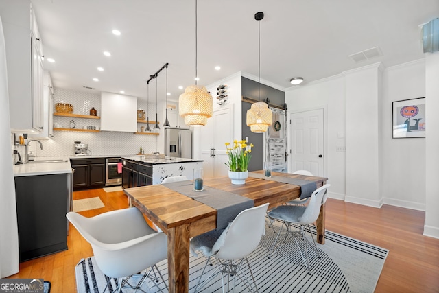 dining area featuring baseboards, visible vents, crown molding, light wood-style floors, and recessed lighting