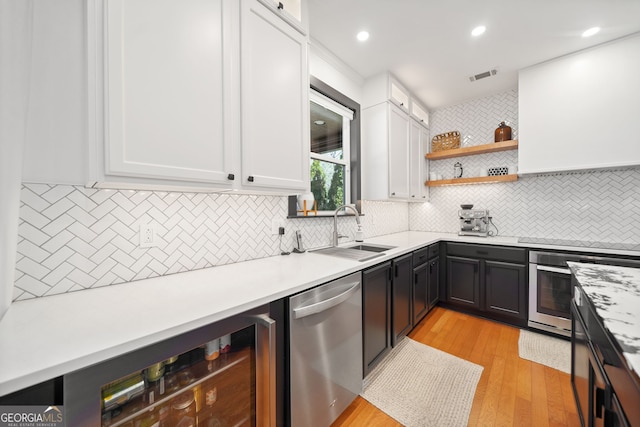 kitchen featuring stainless steel appliances, light countertops, visible vents, white cabinets, and a sink