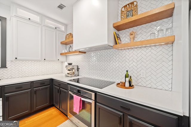 kitchen with visible vents, oven, black electric cooktop, white cabinetry, and open shelves