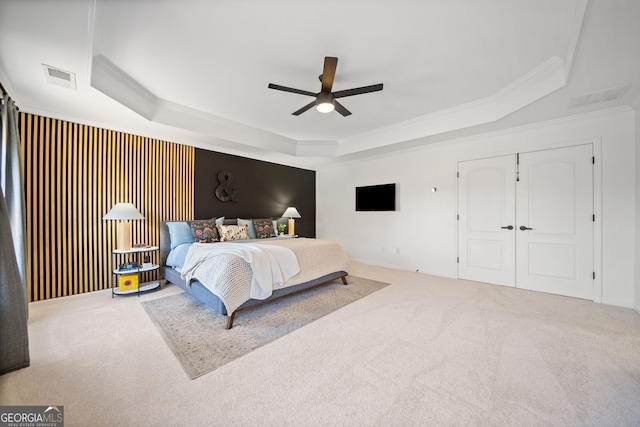 bedroom with carpet floors, visible vents, and a raised ceiling