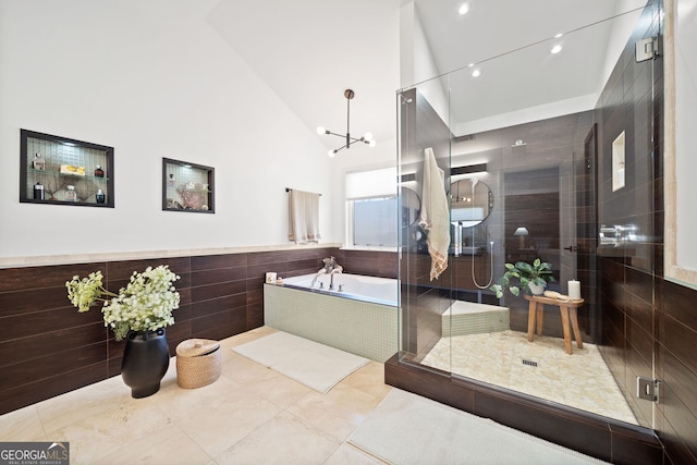 bathroom with tile patterned flooring, a wainscoted wall, tile walls, tiled shower, and a bath