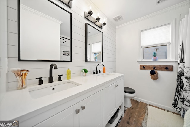 full bath featuring toilet, wood finished floors, a sink, and visible vents