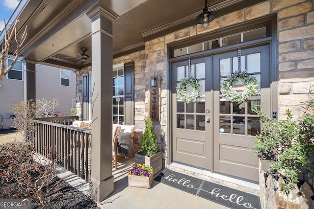 doorway to property with french doors, a porch, and stone siding