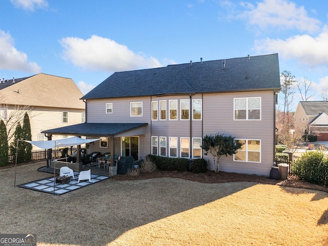 rear view of house with a patio and roof with shingles