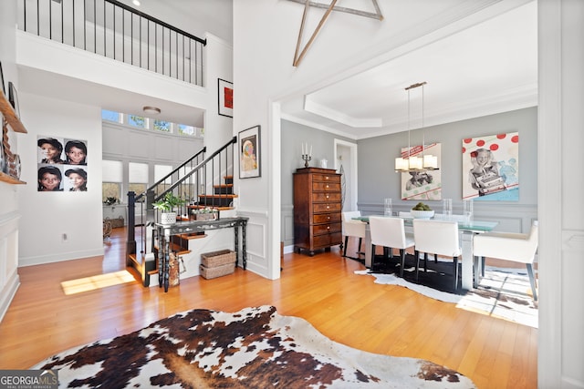 foyer entrance with stairs, a decorative wall, crown molding, and wood finished floors