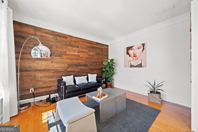 living room featuring ornamental molding, visible vents, baseboards, and wood finished floors