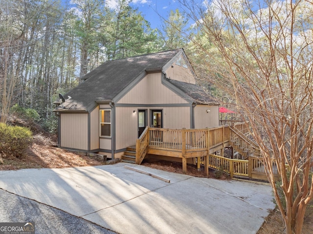 view of front facade with a shingled roof and a wooden deck