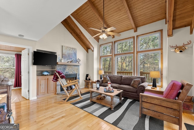living area with high vaulted ceiling, a fireplace, beam ceiling, and light wood-style floors