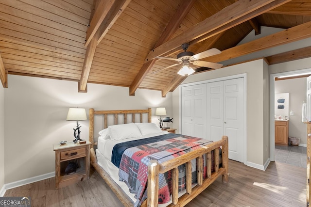 bedroom with vaulted ceiling with beams, light wood-style floors, a closet, and baseboards