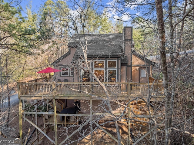 rear view of property with a chimney, a deck, and stairs