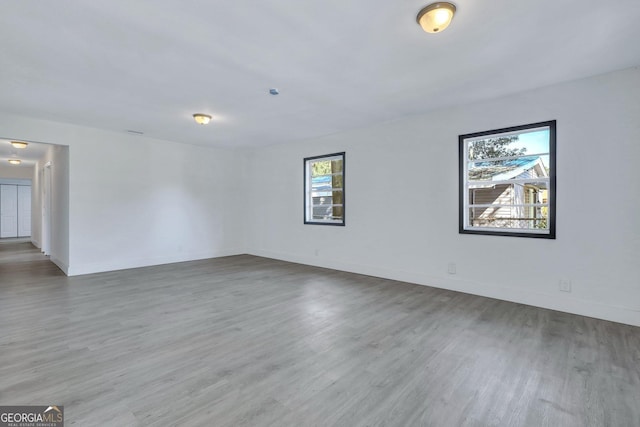 spare room with baseboards and wood finished floors