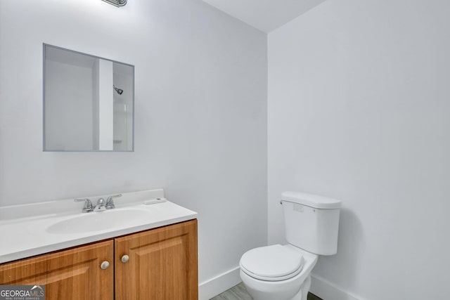 bathroom featuring vanity, toilet, and baseboards