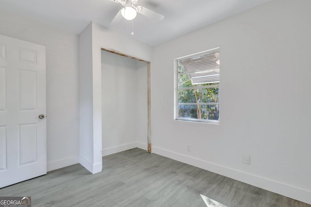 unfurnished bedroom with ceiling fan, a closet, baseboards, and wood finished floors