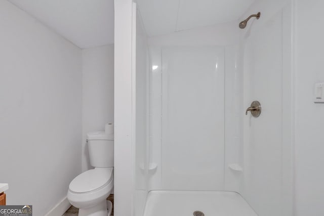 bathroom featuring a stall shower, toilet, and baseboards