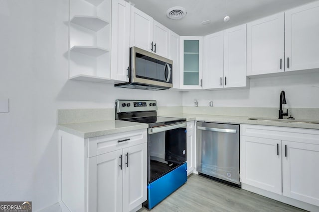 kitchen featuring stainless steel appliances, white cabinetry, a sink, and open shelves