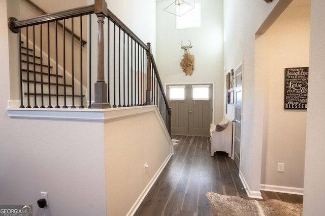 doorway to outside with stairs, hardwood / wood-style floors, a high ceiling, and baseboards