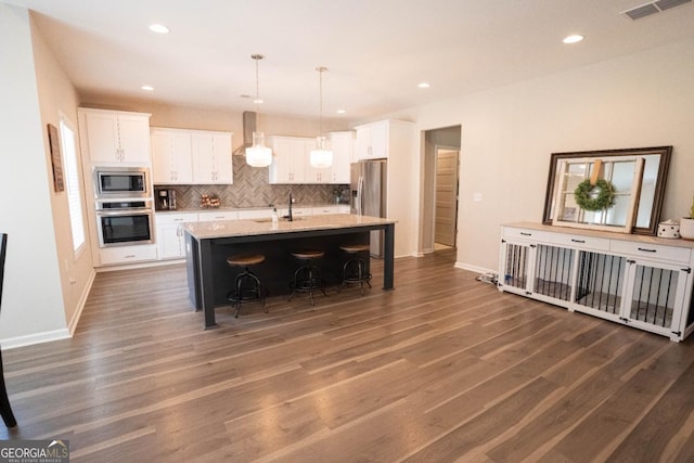 kitchen with appliances with stainless steel finishes, white cabinets, visible vents, and tasteful backsplash
