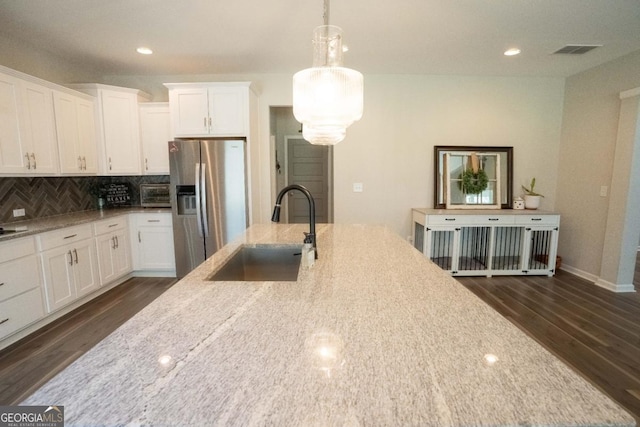kitchen featuring stainless steel fridge, tasteful backsplash, visible vents, dark wood finished floors, and a sink