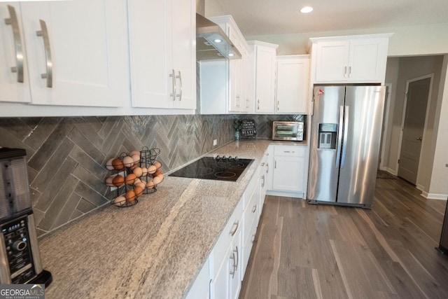 kitchen with white cabinets, wall chimney range hood, stainless steel fridge with ice dispenser, and black electric cooktop