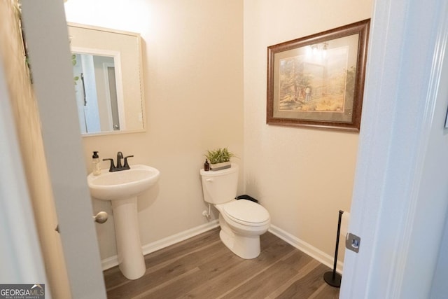 bathroom featuring a sink, wood finished floors, toilet, and baseboards