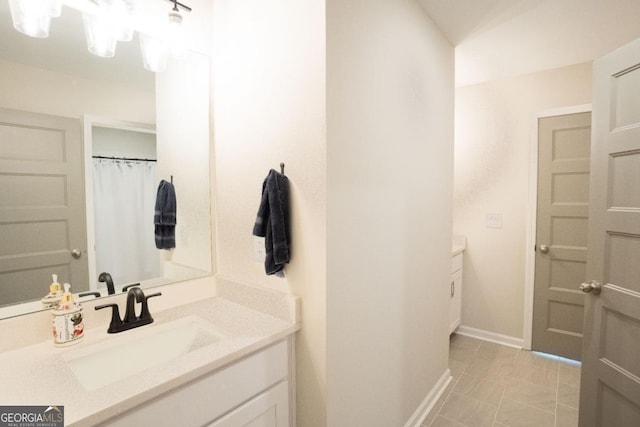 full bath featuring vanity and baseboards