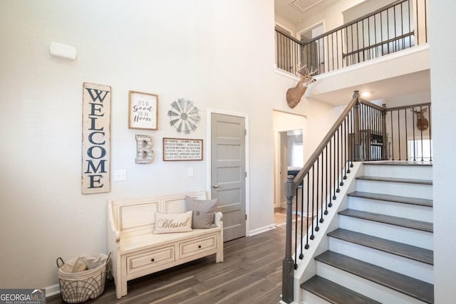 stairs with a towering ceiling, baseboards, and wood finished floors