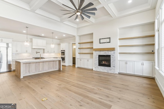 unfurnished living room featuring coffered ceiling, a fireplace, light wood-style floors, ornamental molding, and beam ceiling