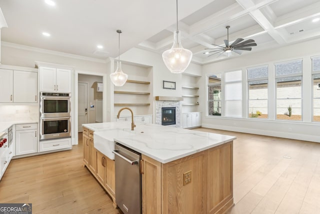 kitchen featuring light wood finished floors, stainless steel appliances, a sink, and open floor plan