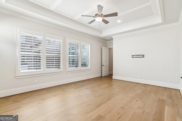 empty room with baseboards, a raised ceiling, ceiling fan, light wood-style flooring, and ornamental molding