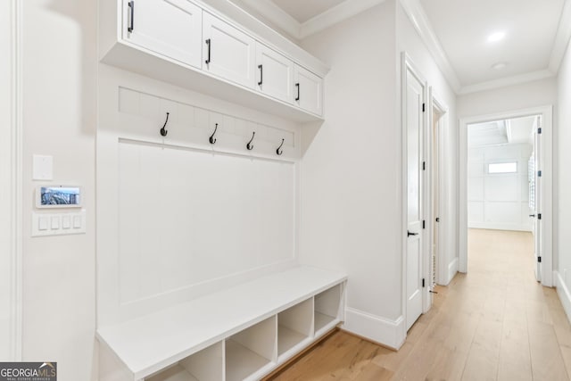 mudroom featuring light wood-style floors, baseboards, and crown molding