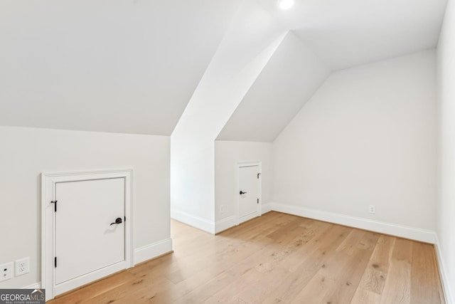 bonus room with light wood-type flooring, lofted ceiling, and baseboards