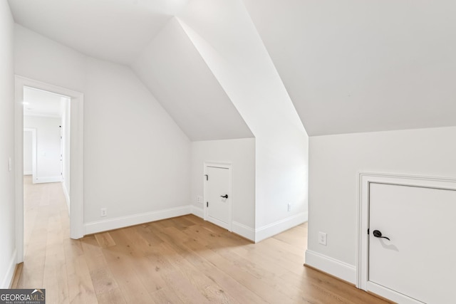 bonus room featuring light wood-style floors, vaulted ceiling, and baseboards