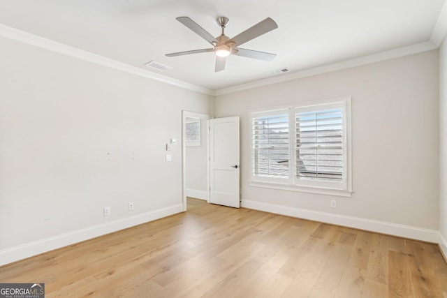 spare room with ornamental molding, light wood-style flooring, visible vents, and baseboards