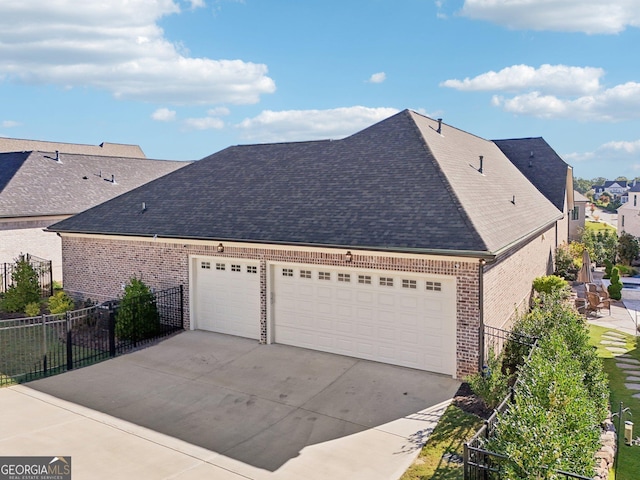 view of front of property with brick siding, roof with shingles, concrete driveway, an attached garage, and fence