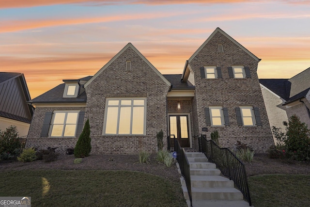 traditional-style home featuring a front lawn, french doors, and brick siding