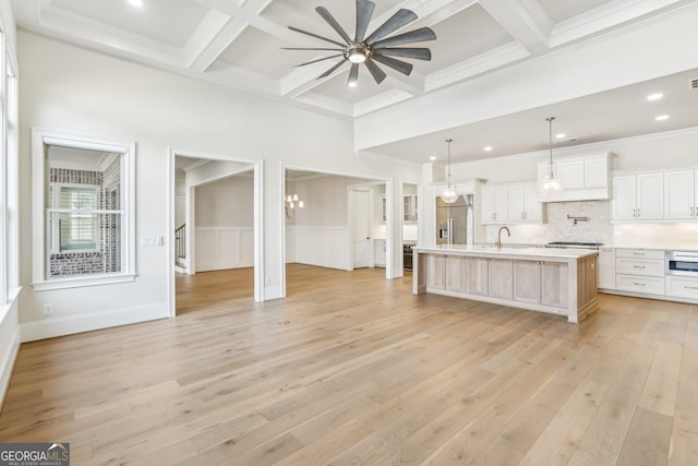 kitchen featuring coffered ceiling, a sink, light countertops, appliances with stainless steel finishes, and beam ceiling