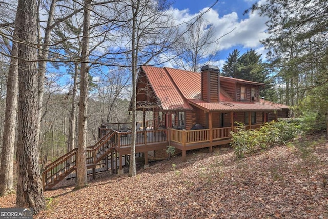 back of house with stairs, metal roof, a chimney, and a wooden deck