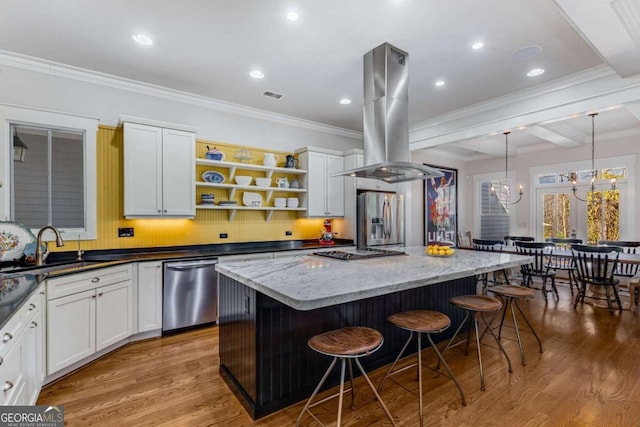 kitchen with appliances with stainless steel finishes, a breakfast bar, a center island, island exhaust hood, and a sink