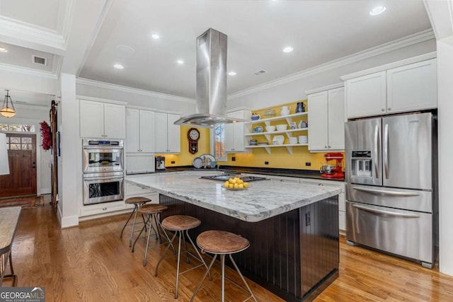 kitchen featuring visible vents, light wood-style flooring, a center island, island exhaust hood, and stainless steel appliances